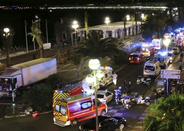 Emergency services vehicles work on the scene after a truck, left, plowed through Bastille Day revelers in the French resort city of Nice (Sasha Goldsmith via AP)