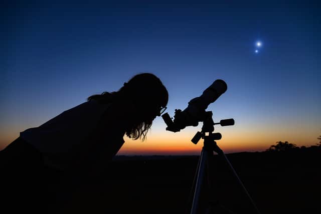 Woman looking at night sky with amateur astronomical telescope.