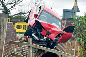 Mangled car left dangling over canal as passenger makes great escape into water 