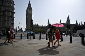 Pedestrians walk in the midday sun past the Palace of Westminster in central London on September 6, 2023 as the late summer heatwave continues.