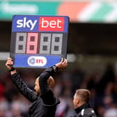 Fourth Official Darren Drysdale holds aloft the substitutes board to show 8 minutes added time 
