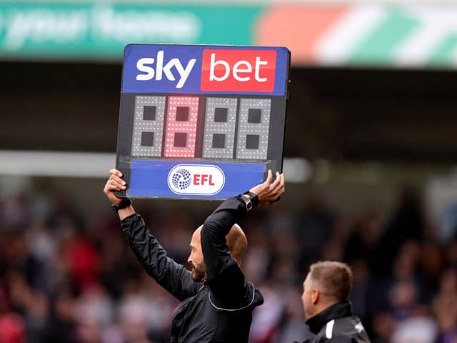 Fourth Official Darren Drysdale holds aloft the substitutes board to show 8 minutes added time 