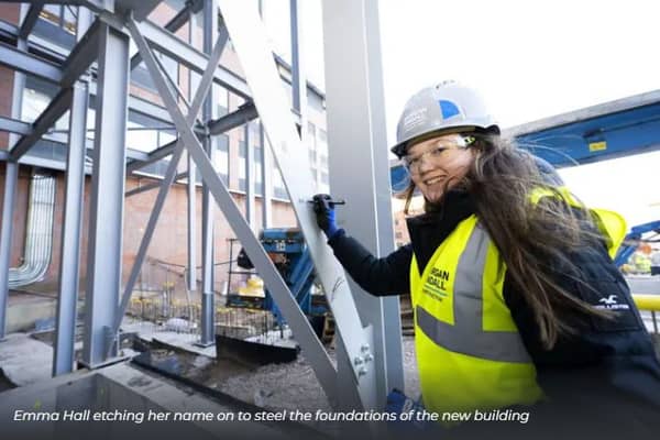 Student Emma Hall puts her name on the steel structure.