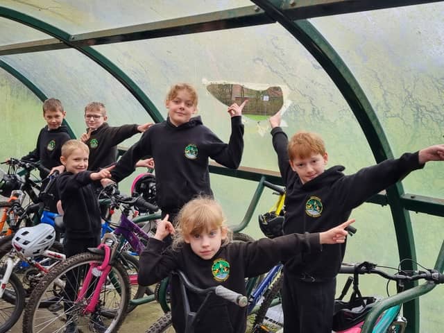 Westwood Primary School pupils pose beside the bike shed vandalism.