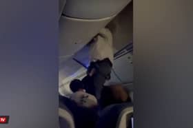 Passengers help man from overhead bin after 'strong turbulence'.