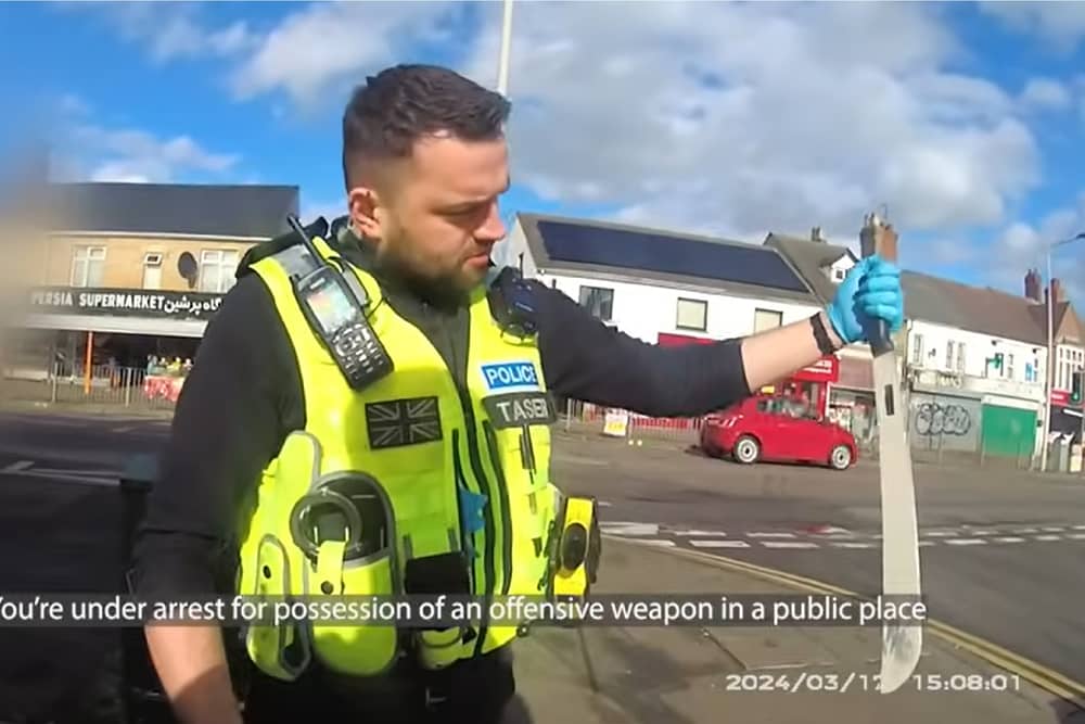 Police officer pulls huge machete from dealer's coat.