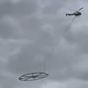 Helicopter carrying large metal circle.