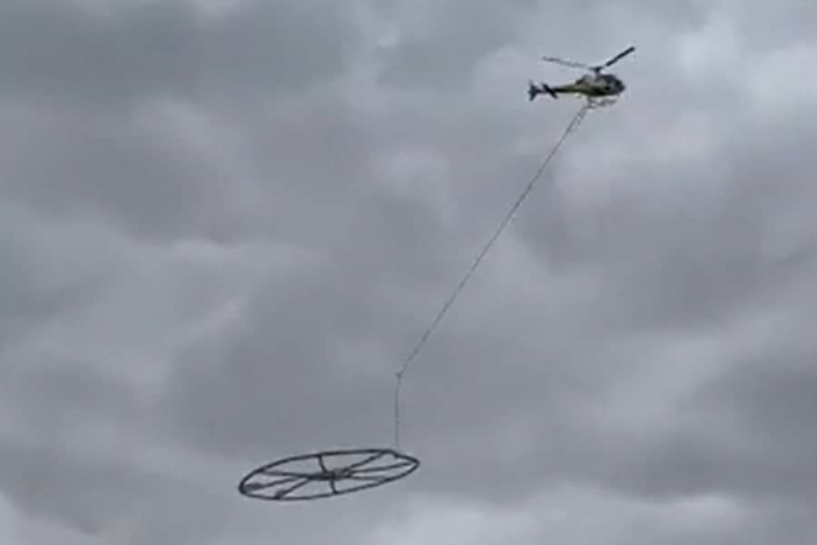 Helicopter carrying large metal circle.