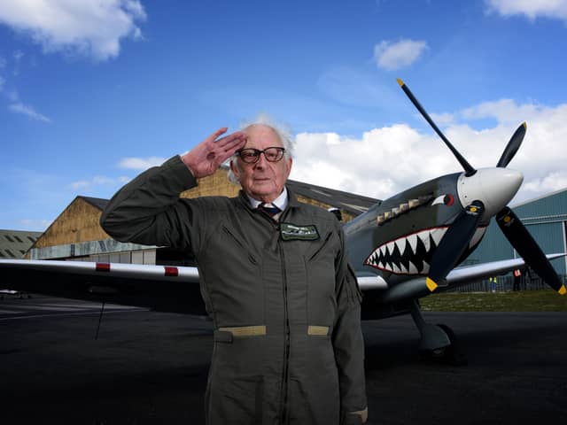 Alan Taylor standing in front of a Spitfire aircraft while saluting