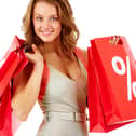 A shopper carrying red sale bags marked with a bold percentage sign, symbolising seasonal discounts and bargain hunting