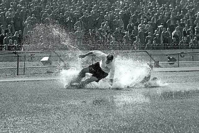 Tom Finney splashes through a puddle on a water-logged pitch