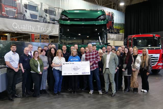 Sarah (seventh from the left) and her husband Michael present Rosemere Cancer Foundation’s Sue Swire (centre) with Sarah’s donation, watched by some of the colleagues who have supported her fundraising