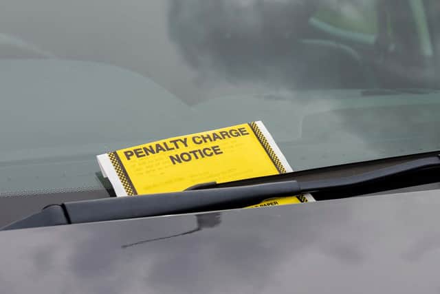 A penalty charge notice parking fine attached to car windscreen