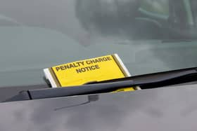 A penalty charge notice parking fine attached to car windscreen
