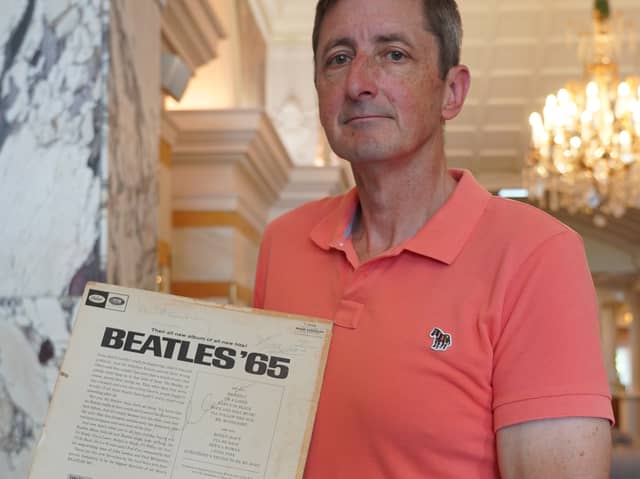 Max Bass pictured holding the Beatles album which his mum got the Beatles to sign in 1965.