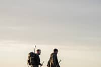 Two figures cross the Ribble Estuary's marshes at dusk. The area's wildfowling traditions are explored in the documentary Call of the Marsh