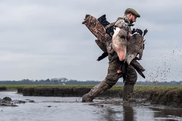 A wildfowler carries shot birds across the Ribble Estuary, where an award-winning documentary explores the relationship between shooting and conservation