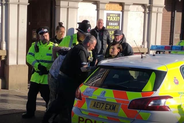 A man is bundled away by police to protect him from the angry after he disrupted a silent tribute with fireworks at a Remembrance Sunday event