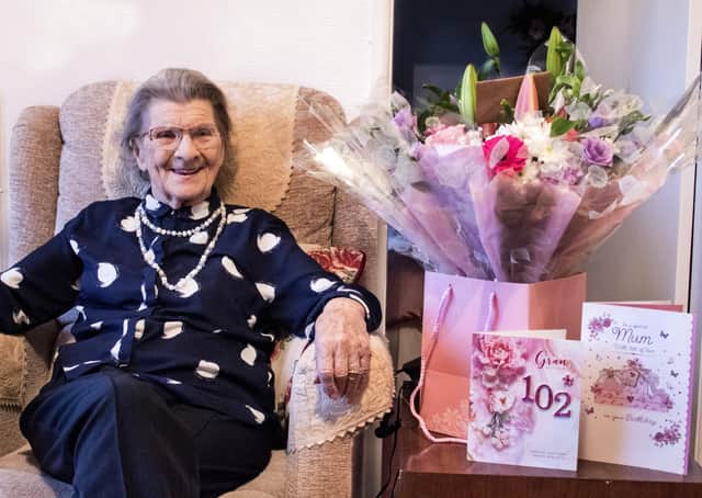 Anne Lane celebrating her 102nd birthday with flowers presented to her by her carers from All About You Care Services. Photo credit: Erynn Pope.