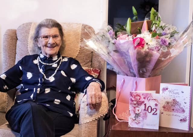 Anne Lane celebrating her 102nd birthday with flowers presented to her by her carers from All About You Care Services. Photo credit: Erynn Pope.