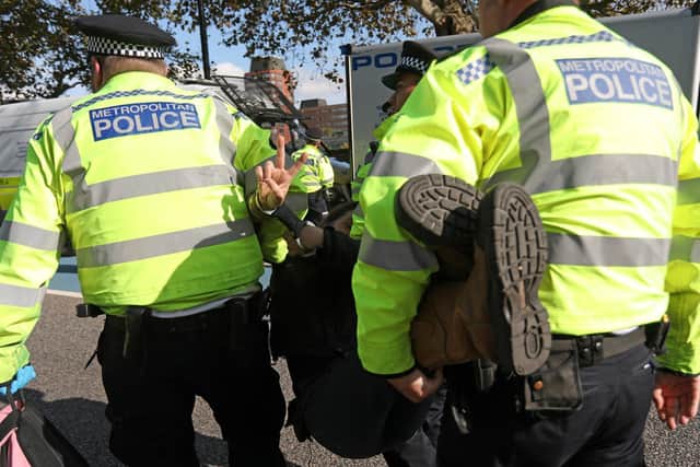 Police officers arrest an activist during a protest, during demonstrations by the climate change action group Extinction Rebellion (Photo by ISABEL INFANTES/AFP via Getty Images)