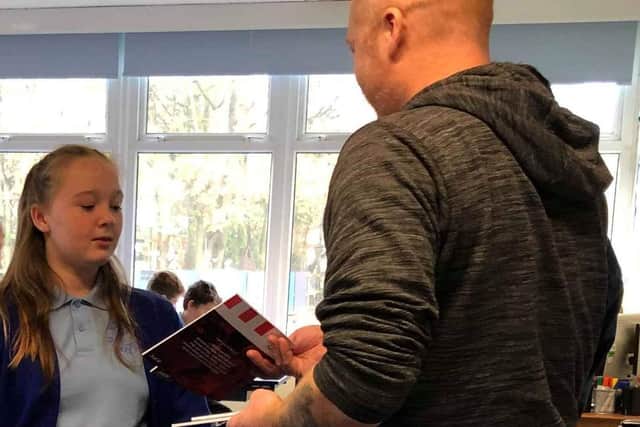 Stuart Clewlow handing out the magazine to his daughter Toria Clewlow who attends Euxton CE Primary School