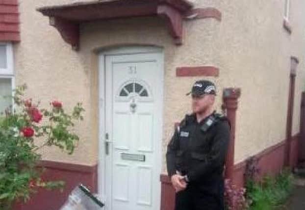 A police officer stands outside property where Mr May was found