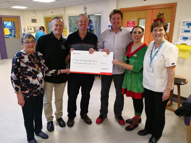 Mick Howarth, Frank Towers and Phil Alcock hand over a cheque to Rookwood A ward at Chorley Hospital after cycling from Denver to Ontario