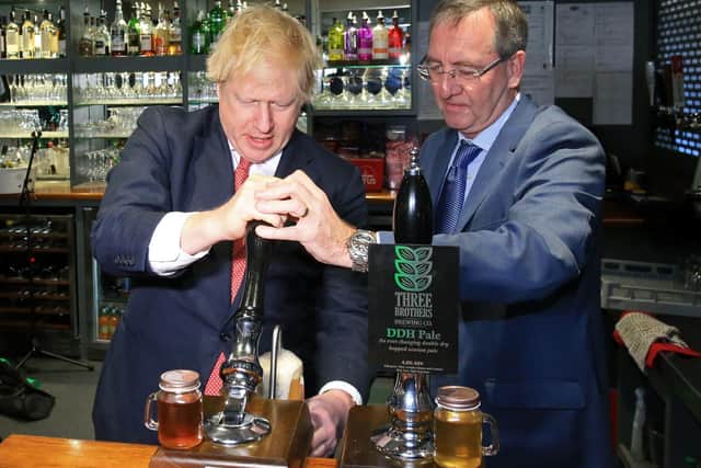 UK Prime Minister Boris Johnson pulls a pint with newly elected Conservative party MP for Sedgefield, Paul Howell at Sedgefield Cricket Club in County Durham (Photo by Lindsey Parnaby - WPA Pool/Getty Images)