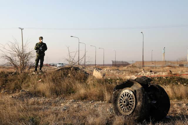 A police officer stands guard as debris is seen from an Ukrainian plane which crashed in Shahedshahr, southwest of the capital Tehran, Iran, Wednesday, Jan. 8, 2020. A Ukrainian airplane carrying 176 people crashed on Wednesday shortly after takeoff from Tehran's main airport, killing all onboard. (AP Photo/Ebrahim Noroozi)