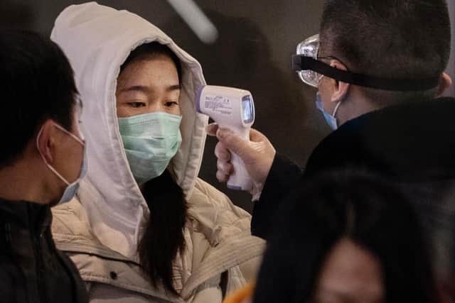 A Chinese passenger that just arrived on the last bullet train from Wuhan to Beijing is checked for a fever by a health worker at a Beijing railway station on January 23, 2020 in Beijing, China (Photo by Kevin Frayer/Getty Images)