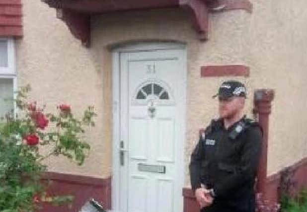 An officer stands outside the address on Raven Street