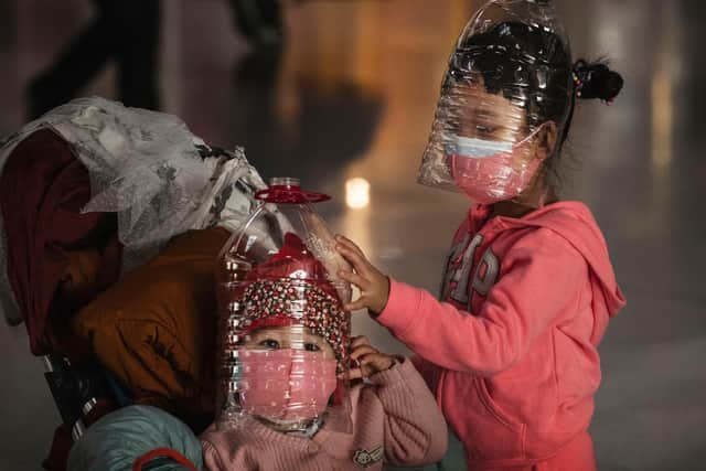 Chinese children wear plastic bottles as makeshift homemade protection and protective masks while waiting to check in to a flight at Beijing Capital Airport on January 30, 2020 in Beijing, China (Picture: Kevin Frayer/Getty Images)