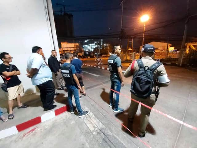 Police and bystanders stand near the scene of a shooting at the Terminal 21 mall, in Korat, Thailand