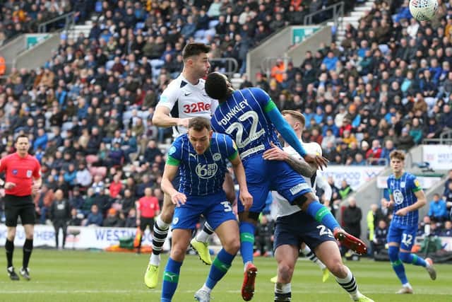 Preston left-back Andrew Hughes challenges in the air against Wigan
