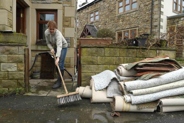Liz Wilkins mopping up outside her home where the water reached 8 inches in her lounge ruining her carpets