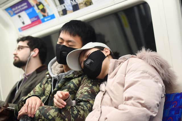 A man and a woman wearing a face masks while traveling on a a tube train on the Jubilee Line of the London Underground.