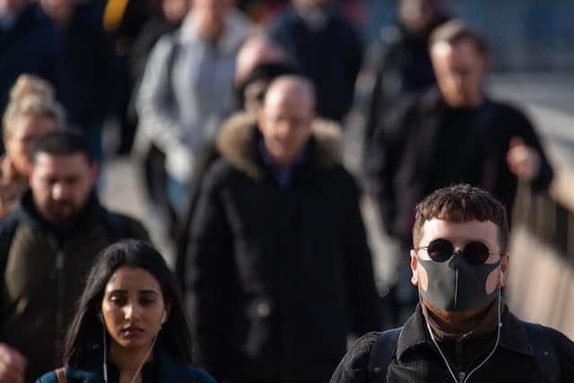 A man wearing a protective face mask as commuters cross London Bridge during morning rush hour in London