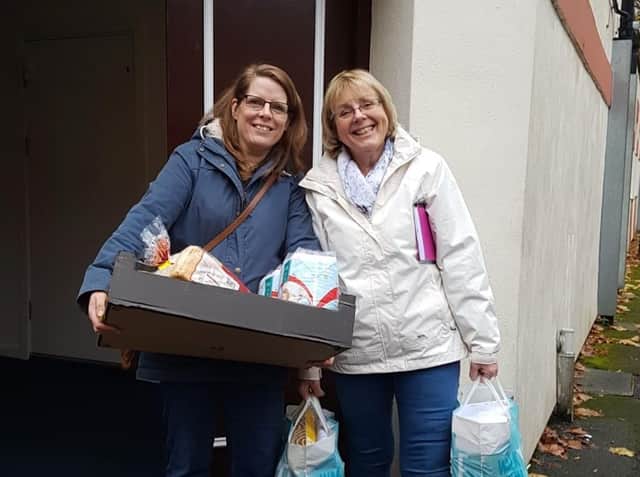 Volunteers Elizabeth Hebson and Bev Redman outside the New Day Church building carrying food bank items to be delivered to clients.
