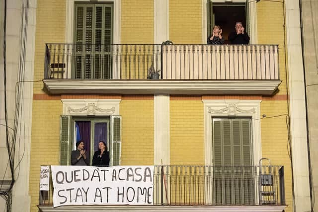 People applaud from a balcony during a flash mob called through social media and messaging platforms, aimed to thank workers in the fight against coronavirus on March 15, 2020 in Barcelona, Spain