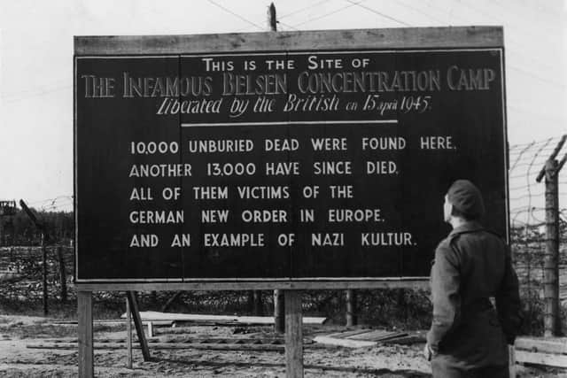 A British soldier reads a billboard posted at the entrance of the Belsen concentration camp. Photo by Hulton Archive/Getty Images