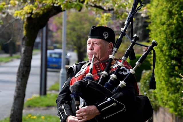 Bob Wilson playing his bagpipes outside his home in Penwortham