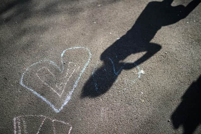 Shadows of children of key workers falls on their chalk drawings (Photo by Christopher Furlong/Getty Images)
