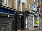 A street sweeper stands outside shuttered shops as the UK continues in lockdown