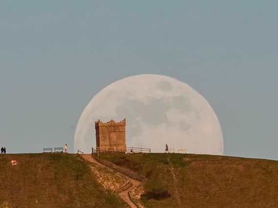 The moon rises over Rivington Pike, Bolton, Lancashire, ahead of the final supermoon of the year
