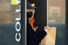 An employee wears a mask to serve customers at a McDonald's drive-thru