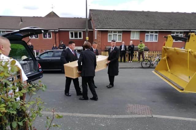 Roy's coffin is carefully carried to be placed in the cradle of the JCB