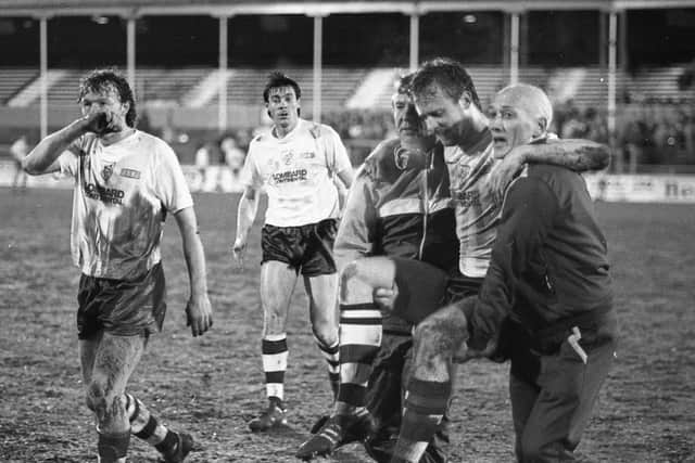 PNE defender Simon Gibson is carried off the pitch in the game against Wrexham, watched by John Thomas and Vernon Allatt