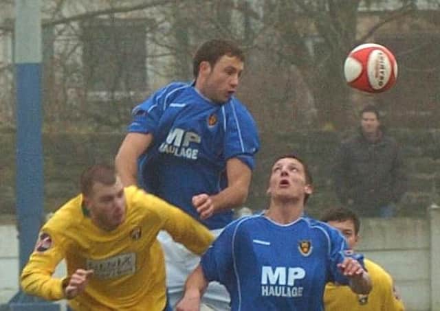 Andy Teague (centre) rises high in his first spell for Lancaster City