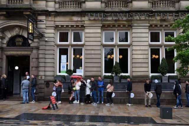 Customers wait patiently in the rain to enjoy a drink at Twelve Tellers in Church Street.